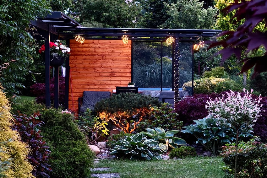 entertaining A cosy wooden garden cabin with a glass door, surrounded by lush green and purple foliage, soft ambient lighting, and a serene, inviting atmosphere.